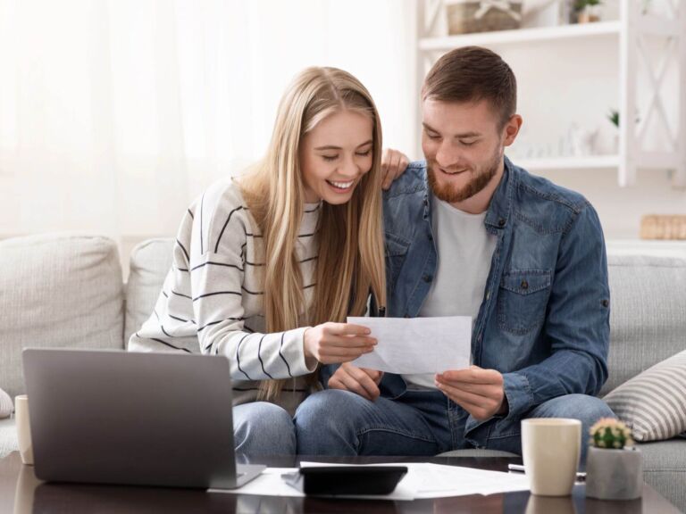 Happy Married Couple Looking At Personal Finances At Home