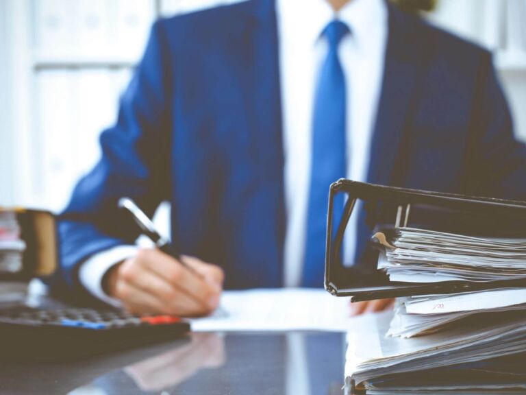 img-writing Binders With Papers Waiting To Be Processed With Businessman Or Bookkeeper Back In Blur. Accounting Planning Budget. Audit, Insurance And Business Concept
